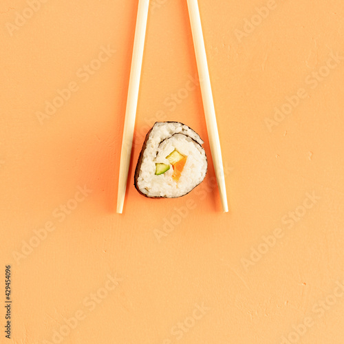 sushi rolls and chopsticks, isolated on orange background