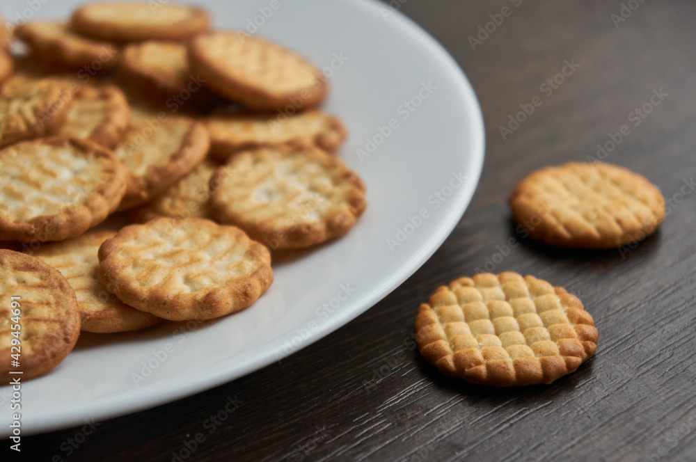 Small round dry cookies on white plate close up Small round dry cookies on white plate close up