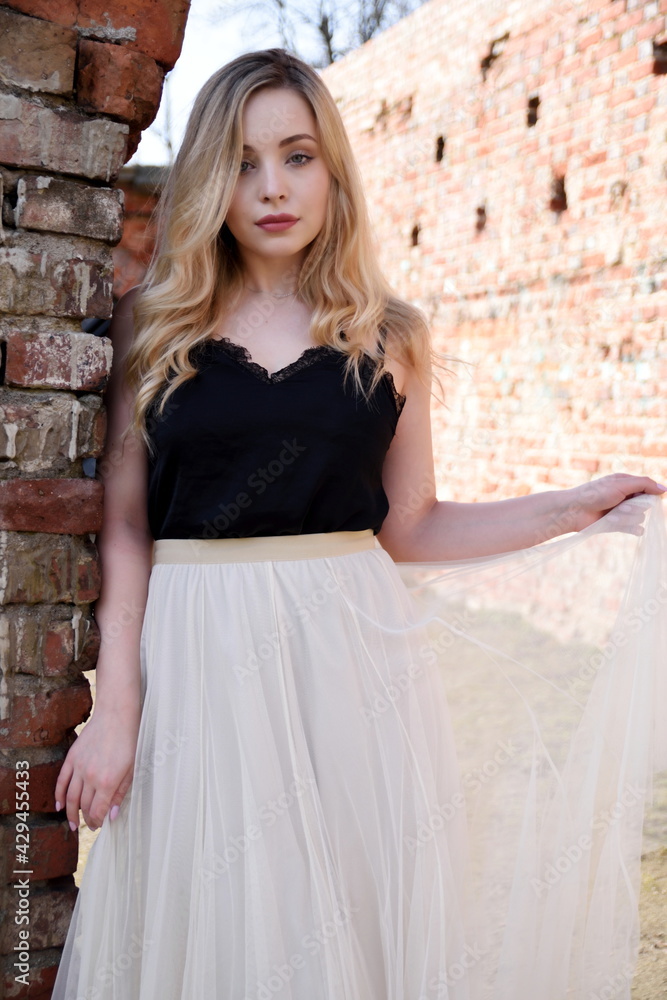 Naklejka premium Young woman in Wroclaw city. Female student with blonde hairs. In the background ruins, red bricks.