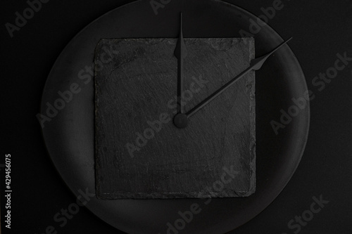 clock tongues on a black ceramic plate, isolated on black. Different shades of black, creative concept.