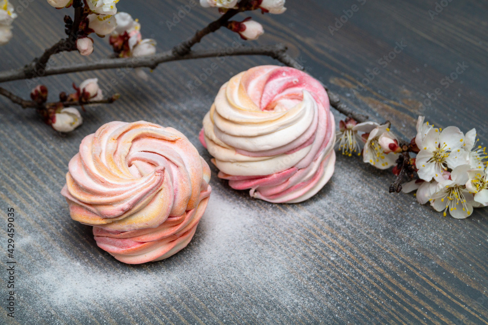 white and pink marshmallow with a blooming apricot branch on a wooden table