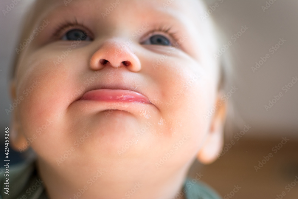 Looking up at the face of cute chubby toddler; bottom lip pushed out and eyes looking skyward