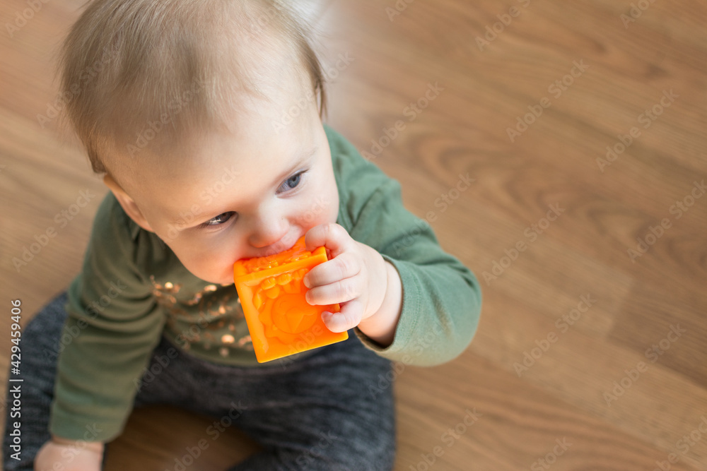 Young toddler chews on soft block toy for teething pain relief Young toddler chews on soft block toy for teething pain relief