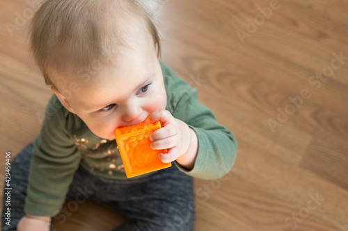 Young toddler chews on soft block toy for teething pain relief