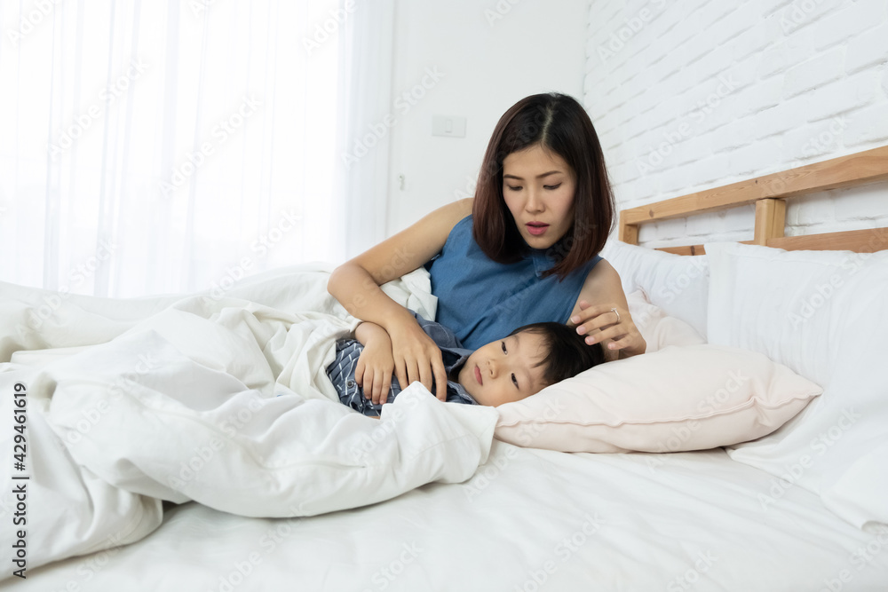 Portrait of beautiful young asian mother lulling her child sleep in bed. Love and Mother's day concept.. Portrait of beautiful young asian mother lulling her child sleep in bed. Love and Mother's day concept..