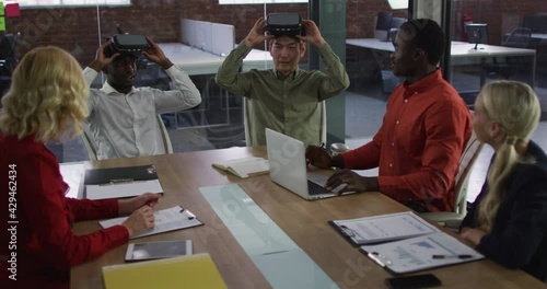 Diverse group of business colleagues sitting in meeting room using vr headset applauding photo