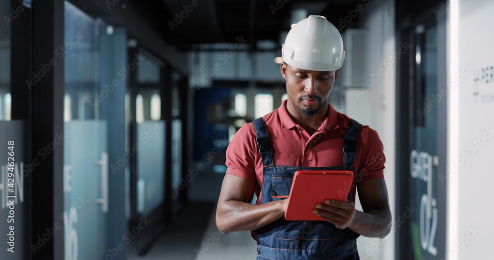 Diverse couple of adult and young electricians coworking in corporate office center repairing lighting electric system using tablet computer for management. Diverse couple of adult and young electricians coworking in corporate office center repairing lighting electric system using tablet computer for management.