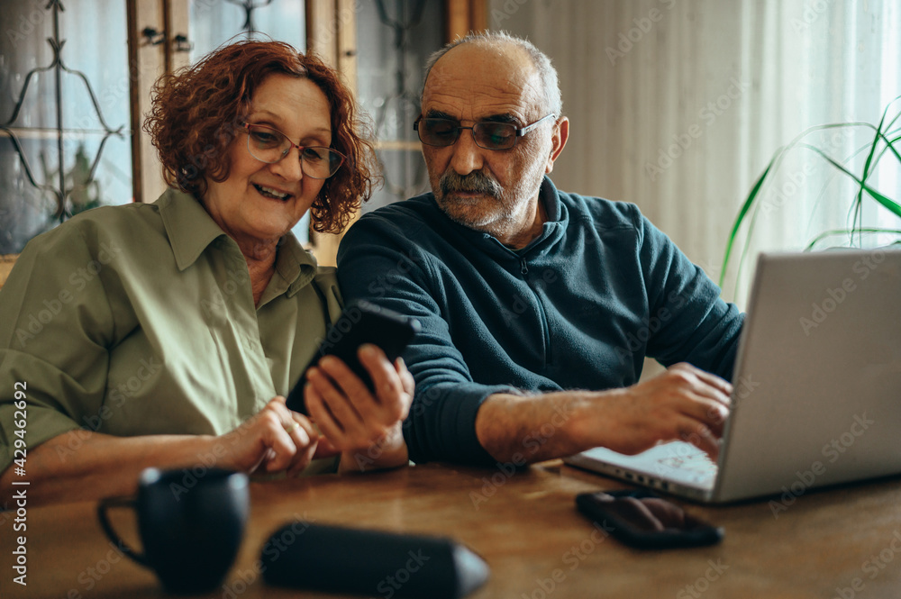 Senior couple using a smartphone and a laptop Senior couple using a smartphone and a laptop