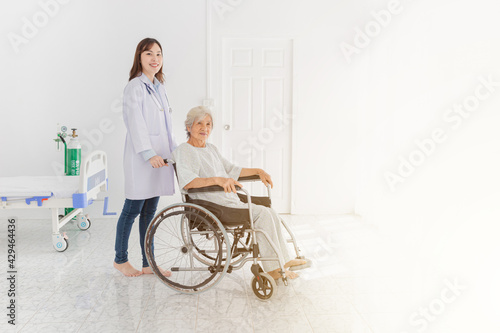 close up patient, Asian doctor drive a wheelchair of old patient, doctor and old female talk about disease symptoms and treatment plan, happy hospital, elderly healthcare promotion