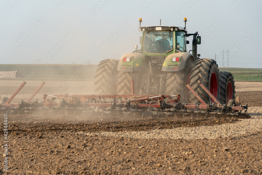 Fototapeta premium A large tractor with a plow is working in the field. Tillage before sowing. Loosening and plowing the soil before planting wheat and other cereals. Agricultural work.