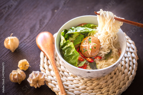 Chopsticks pick up noodles from a vegetarian noodles bowl photo