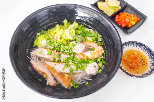 Vietnamese food - Rice noodle soup with seafood topping and vegetables in black bowl