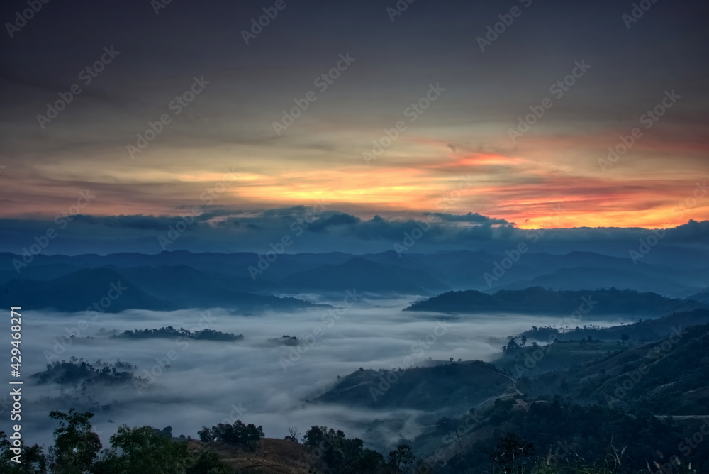 Fluffy fog stream is covering a valley with colorful twilight sky in a morning