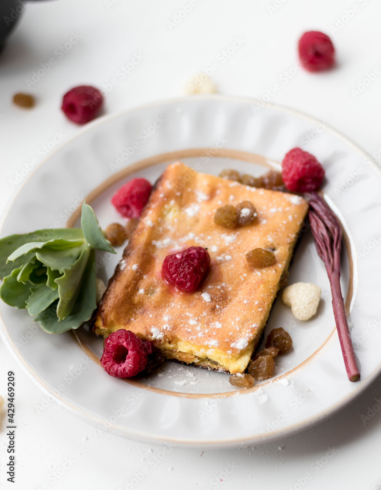 Appetizing curd casserole. Nearby is a drink and raspberries with raisins. Appetizing curd casserole. Nearby is a drink and raspberries with raisins.