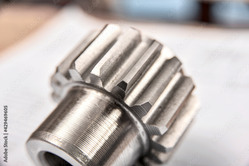 A cogwheel made on a gear cutting machine lies on the technical drawings. A cogwheel made on a gear cutting machine lies on the technical drawings.