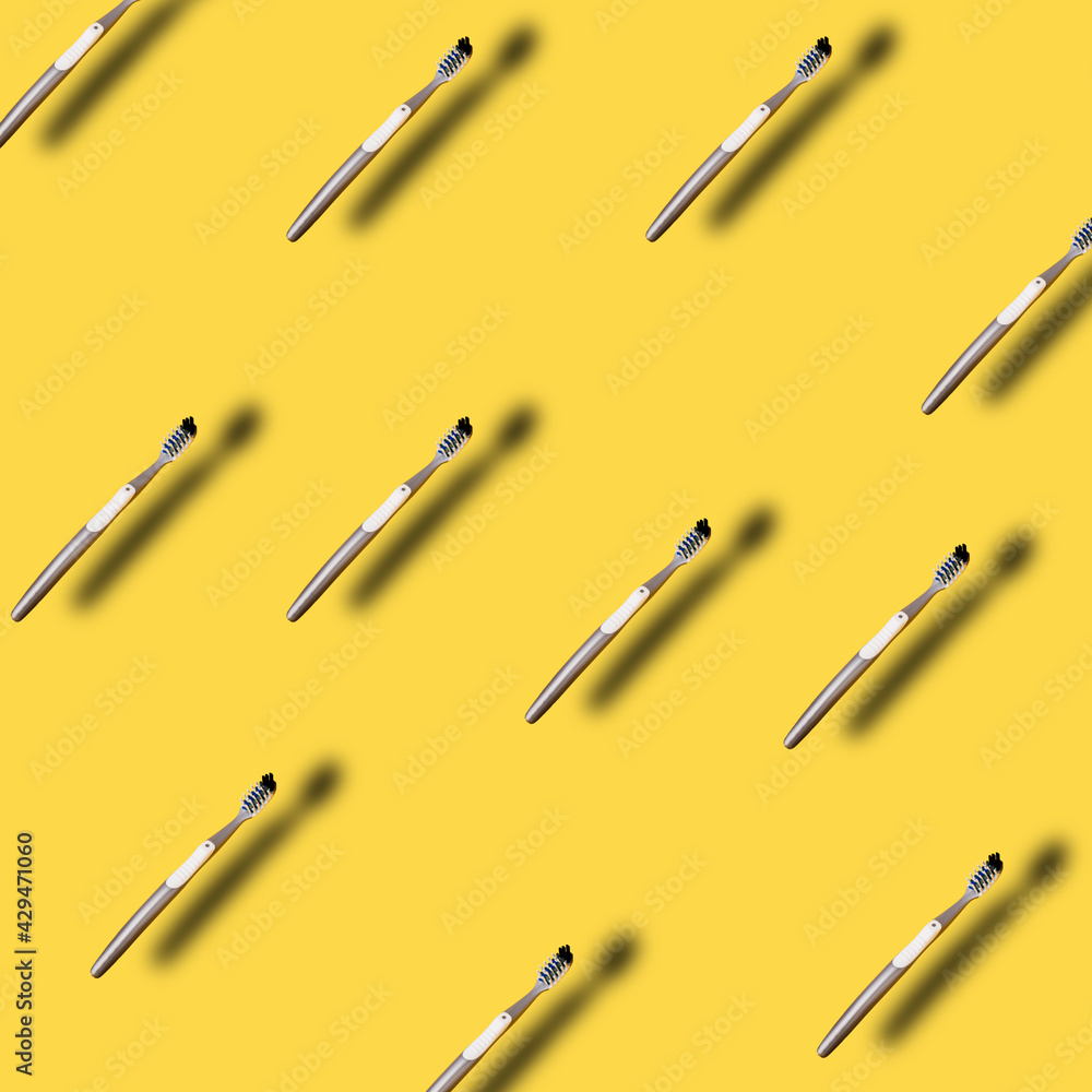 Pattern made with many Toothbrush on yellow backdrop with trendy summer shadows. Oral care hygiene, trendy stylish health concept. Flat lay, top view background.