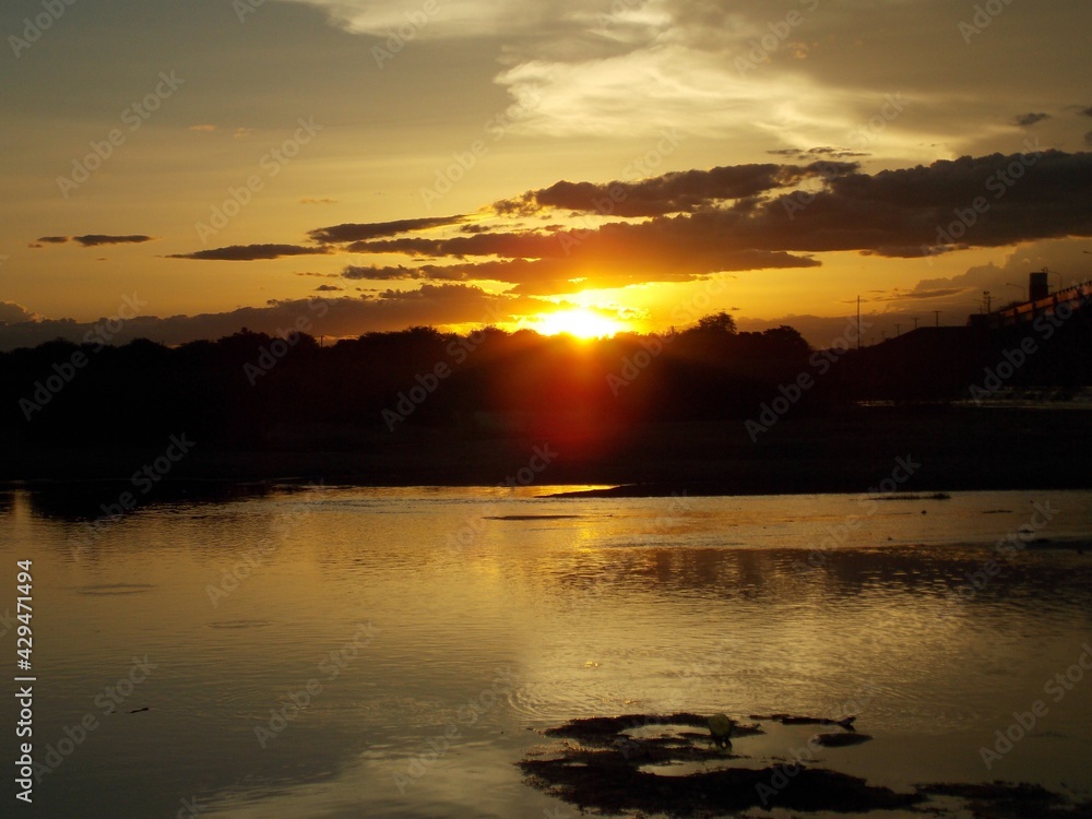 Hermoso ocaso, atardecer, puesta del sol en Islas del Río Paraná, en Argentina, reflejado en el agua