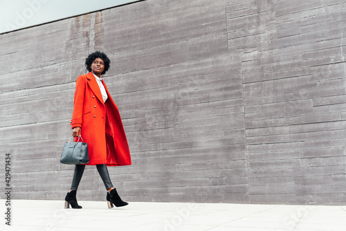 Fashionable black woman in red coat walking