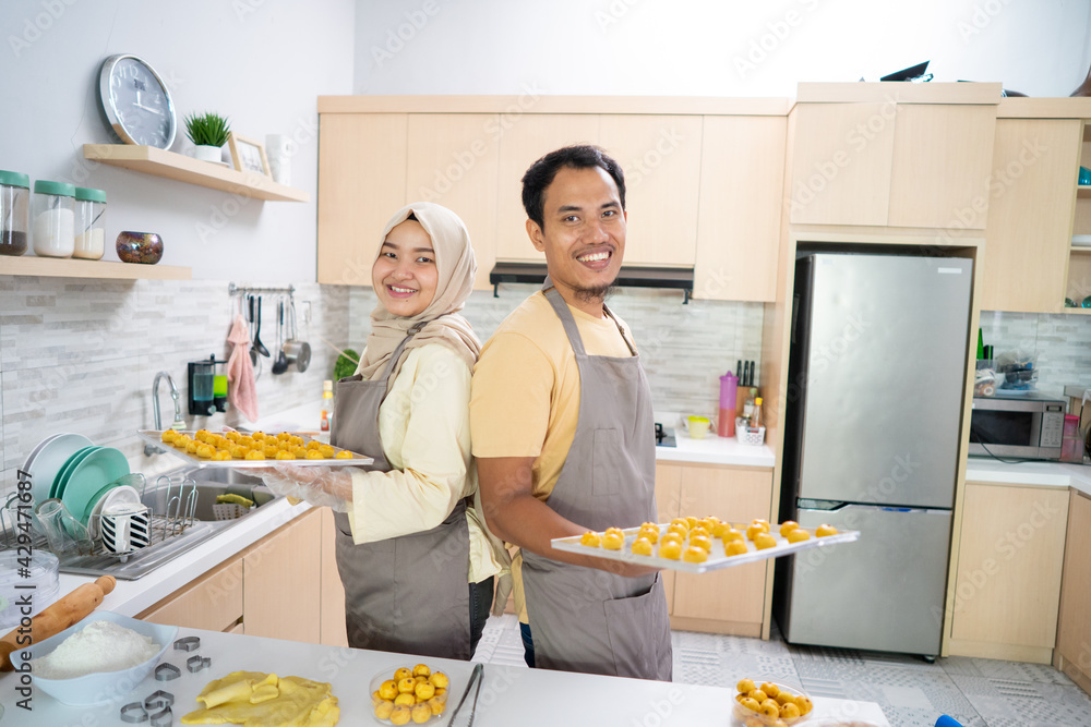 asian muslim couple making nastar snack cake together in the kitchen during ramadan for eid celebration mubarak with family. indonesian food traditonal asian muslim couple making nastar snack cake together in the kitchen during ramadan for eid celebration mubarak with family. indonesian food traditonal