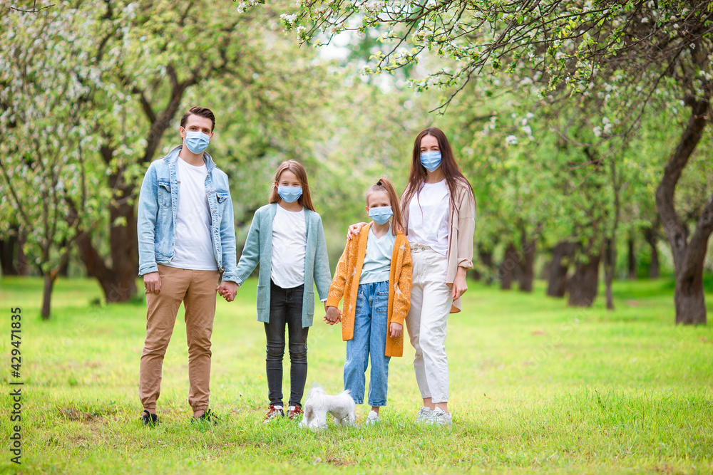 Adorable family in blooming cherry garden in masks Adorable family in blooming cherry garden in masks