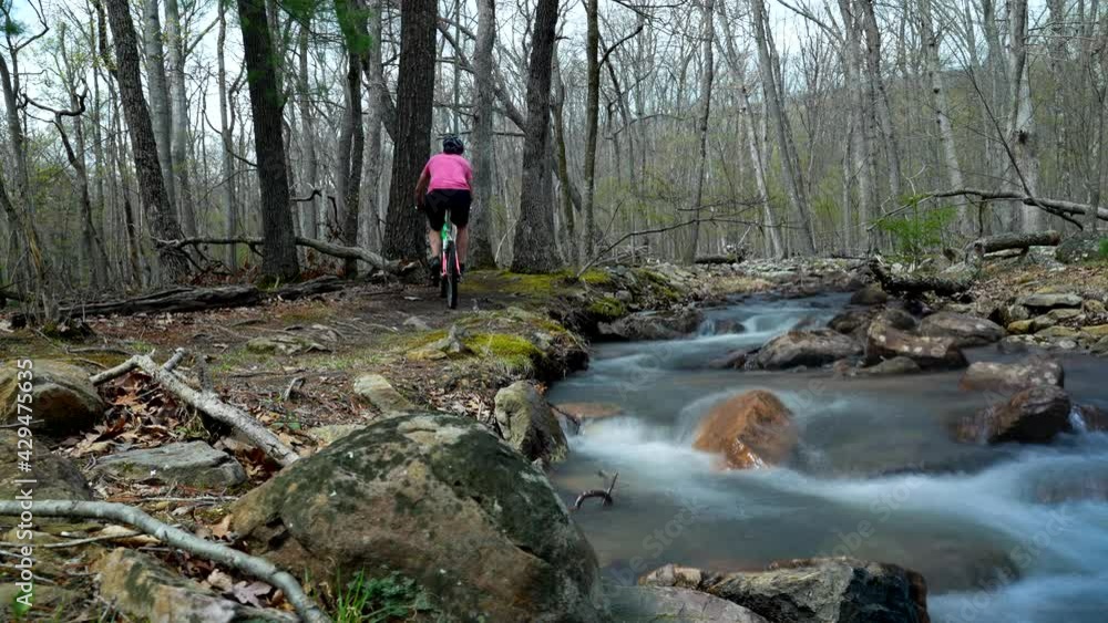 Cinemagraph of man biking along a raging river. Unrecognizable young ...
