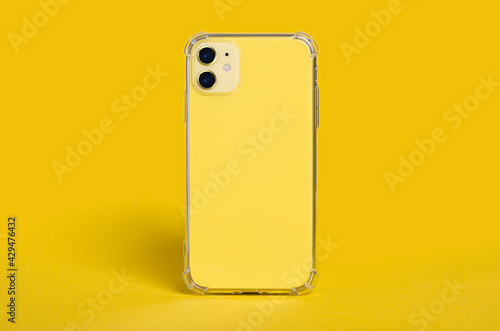 Yellow iPhone 11 in clear silicone case back view. Phone case mockup isolated on yellow background