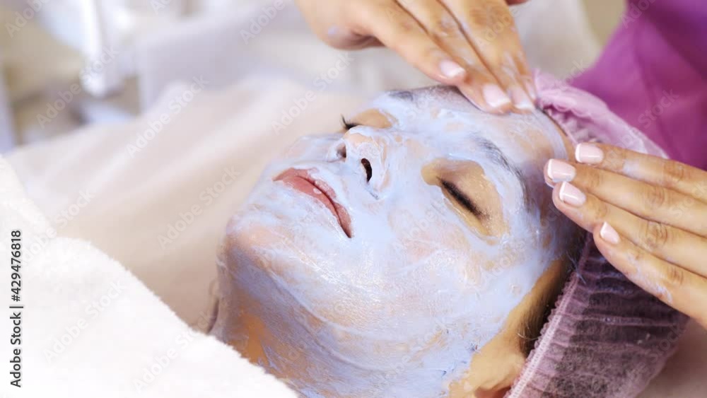Beautician makes a massage of face with a moisturizing cream. Cosmetologist doing a woman a therapeutic massage on face. Beautician makes a massage of face with a moisturizing cream. Cosmetologist doing a woman a therapeutic massage on face.