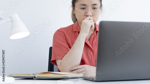 Asian business woman in a bright t-shirt is working at home, Stay home, New normal, Covid-19 coronavirus, Social distancing, Coming up with ideas for work, Writing information in a notebook.