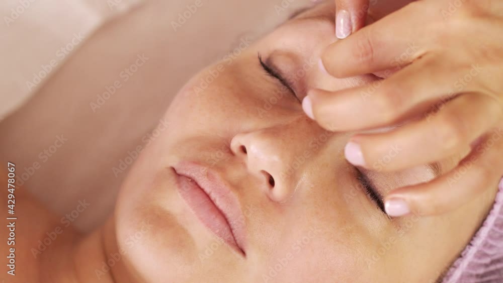 Beautician makes a massage of female face. Cosmetologist doing a woman a therapeutic massage on her face. Woman in a spa salon on cosmetic procedures. Beautician makes a massage of female face. Cosmetologist doing a woman a therapeutic massage on her face. Woman in a spa salon on cosmetic procedures.