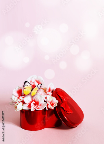 Heart shape gift box and bouquet with butterfly on pink background. photo