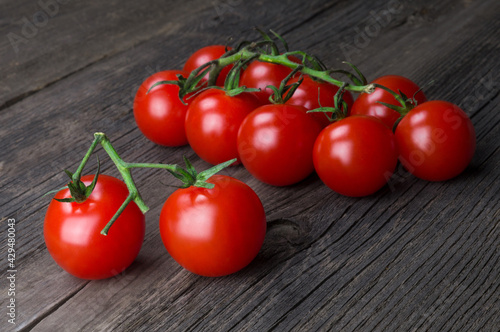 Bunch of ripe delicious red cherry tomatoes close-up on wooden background