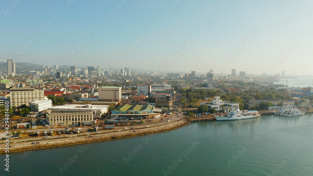 Panorama of Cebu City, seaport with ships and ferries and modern skyscrapers and residential buildings. Philippines.