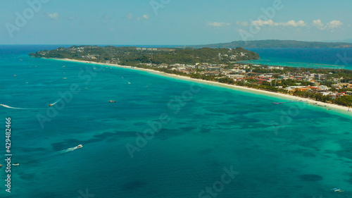 Tropical white beach with tourists and hotels near the blue sea, aerial view. Summer and travel vacation concept.