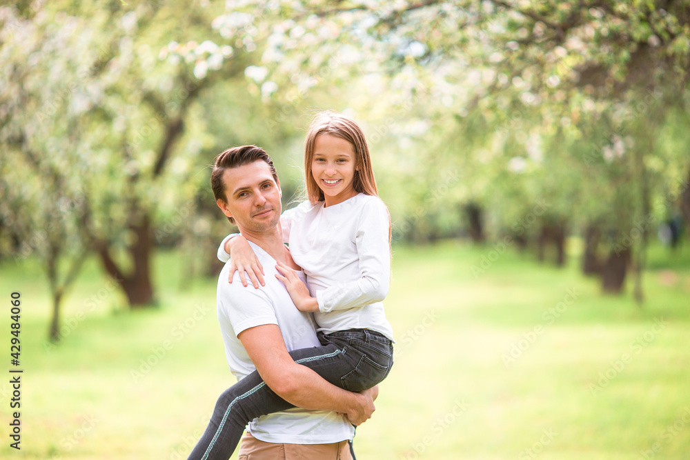 Naklejka premium Family of father and daughter in blooming cherry garden
