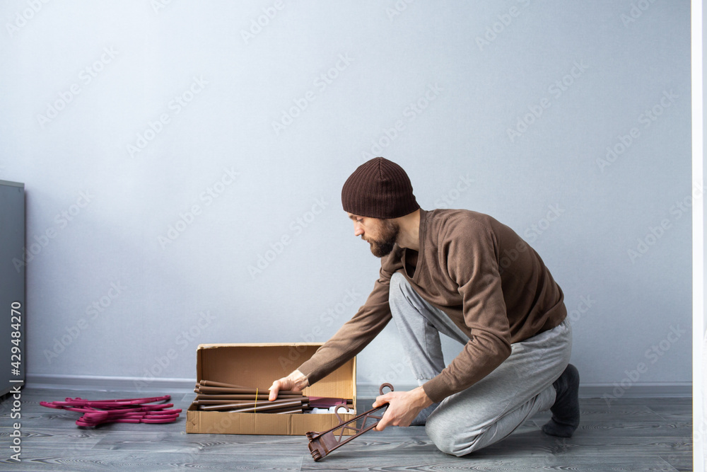 Fototapeta premium bearded man unpacks a box of furniture parts.