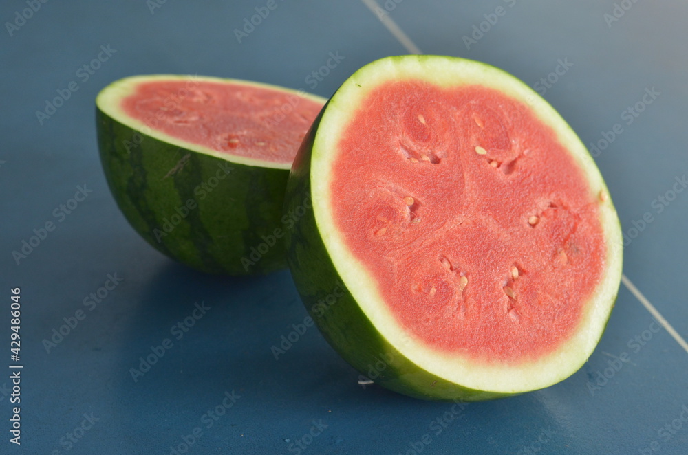 whole and half watermelon isolated in blue background whole and half watermelon isolated in blue background