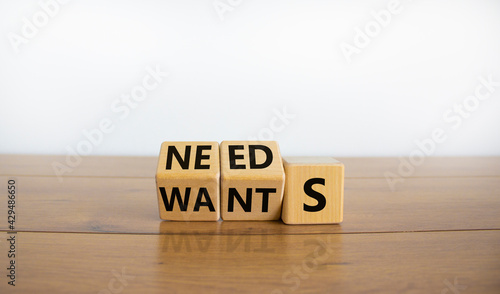 Wants or needs symbol. Turned cubes and changed the word 'wants' to 'needs'. Beautiful wooden table, white background, copy space. Valentines day and wants or needs concept. photo