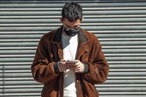 young man with mask and mobile phone on the street