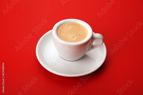 white cup of coffee with foam on red background