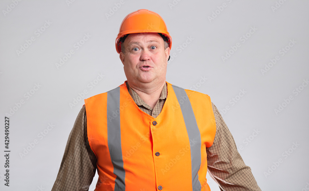 fat construction worker in funny confusion in helmet on grey background, bulder does not understand with humorous face expression fat construction worker in funny confusion in helmet on grey background, bulder does not understand with humorous face expression