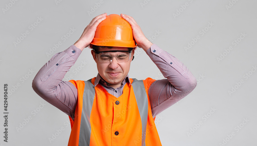 young engineer architect clutching his head in helmet on grey studio background, foreman shocked young engineer architect clutching his head in helmet on grey studio background, foreman shocked