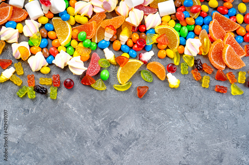 Sweets and candies background. Different candies, marshmallows, marmalade, yummi gummi scattered on the table. Top view.