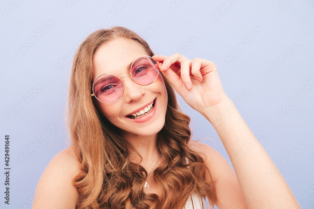 Young beautiful smiling female in trendy summer hipster clothes. Sexy carefree woman posing near purple wall in studio. Positive model having fun indoors. Taking pov selfie photos in sunglasses Young beautiful smiling female in trendy summer hipster clothes. Sexy carefree woman posing near purple wall in studio. Positive model having fun indoors. Taking pov selfie photos in sunglasses