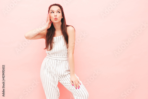 Portrait of young beautiful smiling female in trendy summer hipster clothes. Sexy carefree woman posing near pink wall in studio. Positive model having fun indoors. Cheerful and happy © halayalex