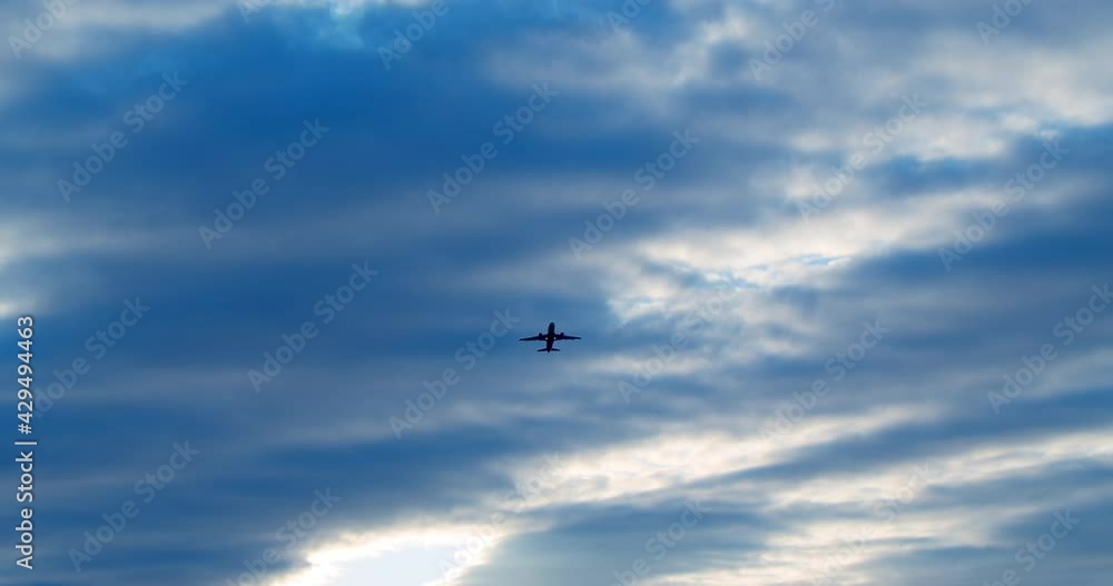 Silhouette of a passenger plane against a background of blue and white clouds. Silhouette of a passenger plane against a background of blue and white clouds.