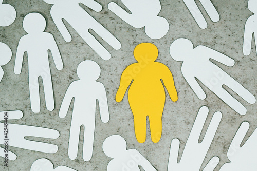 An overweight person among ordinary people. Paper-cut silhouettes. Nutrition and weight control, health care.