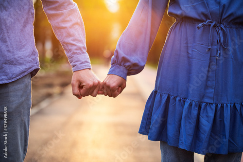 Young couple in love walking in the autumn park holding hands looking in the sunset
