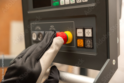 Emergency shutdown button in production. The CNC operator presses the emergency button on the control panel of the CNC machine. Place for text photo