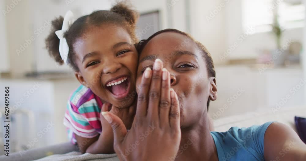 Happy african american mother and daughter taking selfie giving air kisses at home Happy african american mother and daughter taking selfie giving air kisses at home