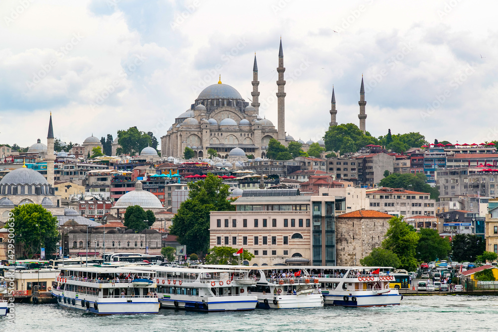 Istanbul cityscape with boats and Suleymaniye Mosque (Ottoman imperial mosque). Old town with colored buildings. Eminonu Ferryboat docks facing the mouth of the Golden Horn Bay.View from Galata bridge